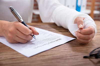 guy with broke arm signing workers comp papers